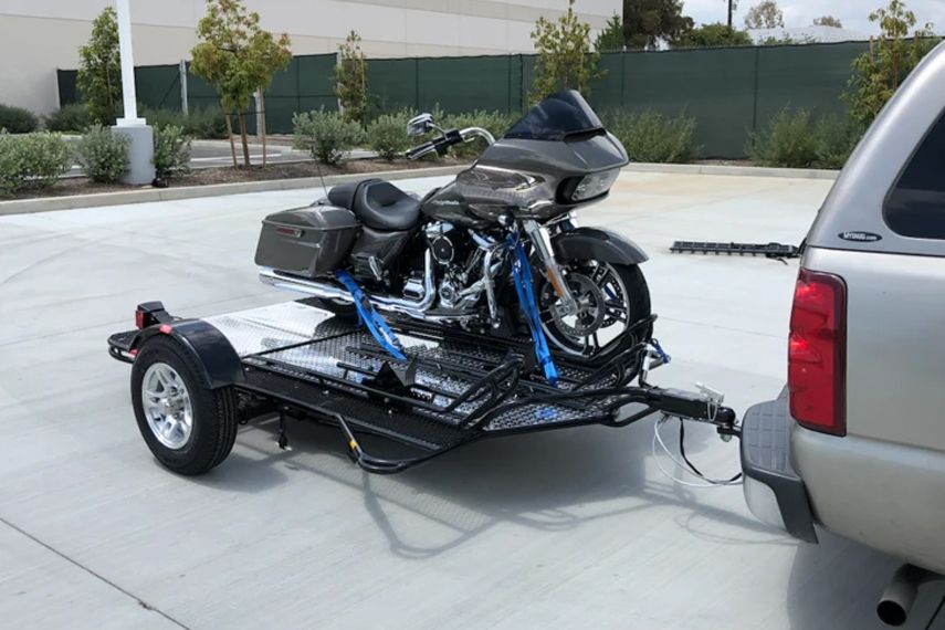 A motorcycle is being towed on a trailer by a truck.