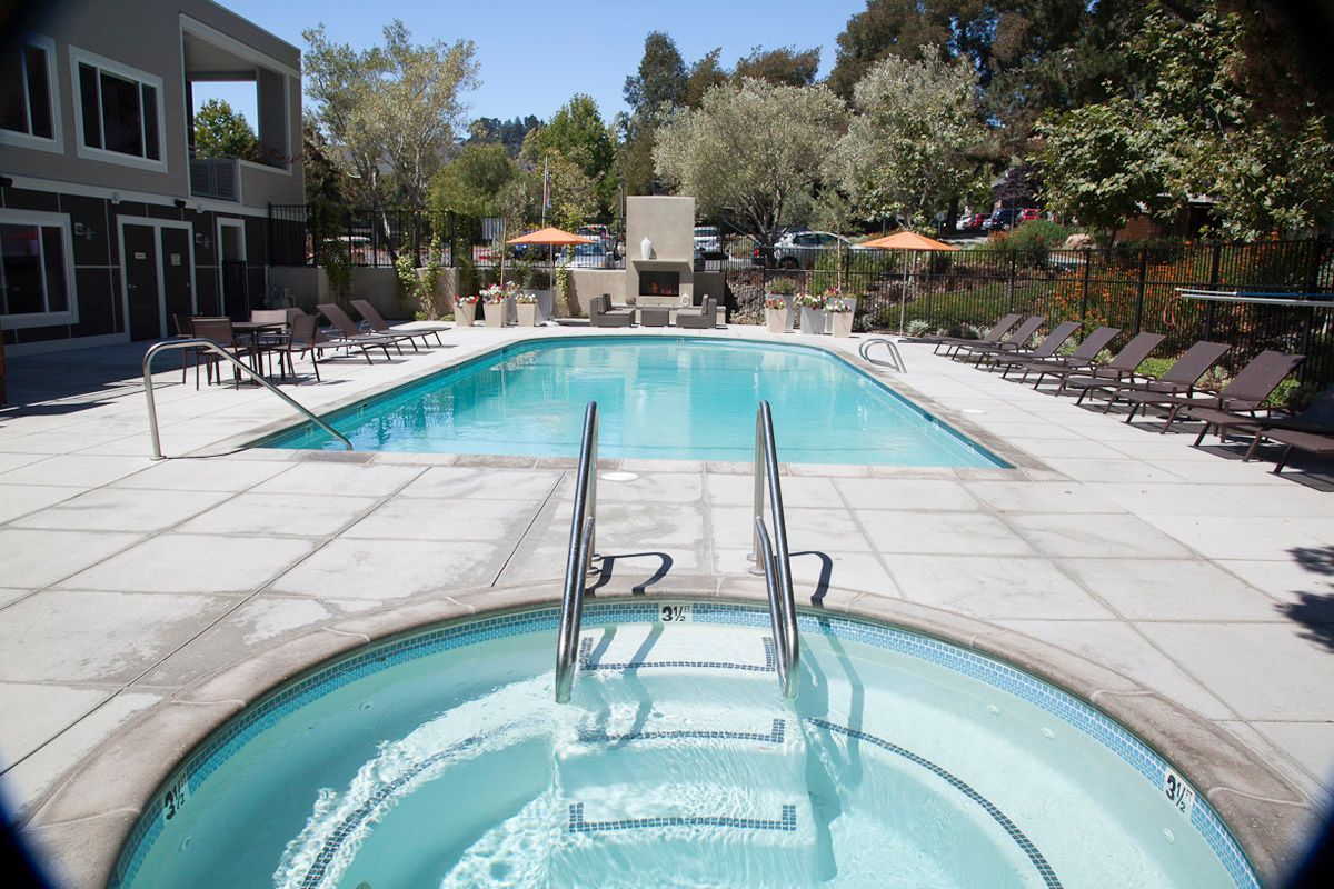 Pool and hot tub with lounge chairs in an outdoor residential setting.
