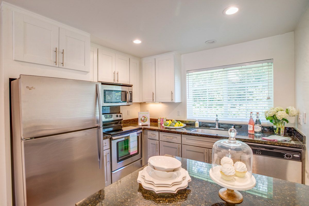 Bright modern kitchen with white cabinets, stainless appliances, and a large window. View our 1- and 2-bedroom homes and townhomes at Finch at Larkspur in scenic Larkspur, CA.  
