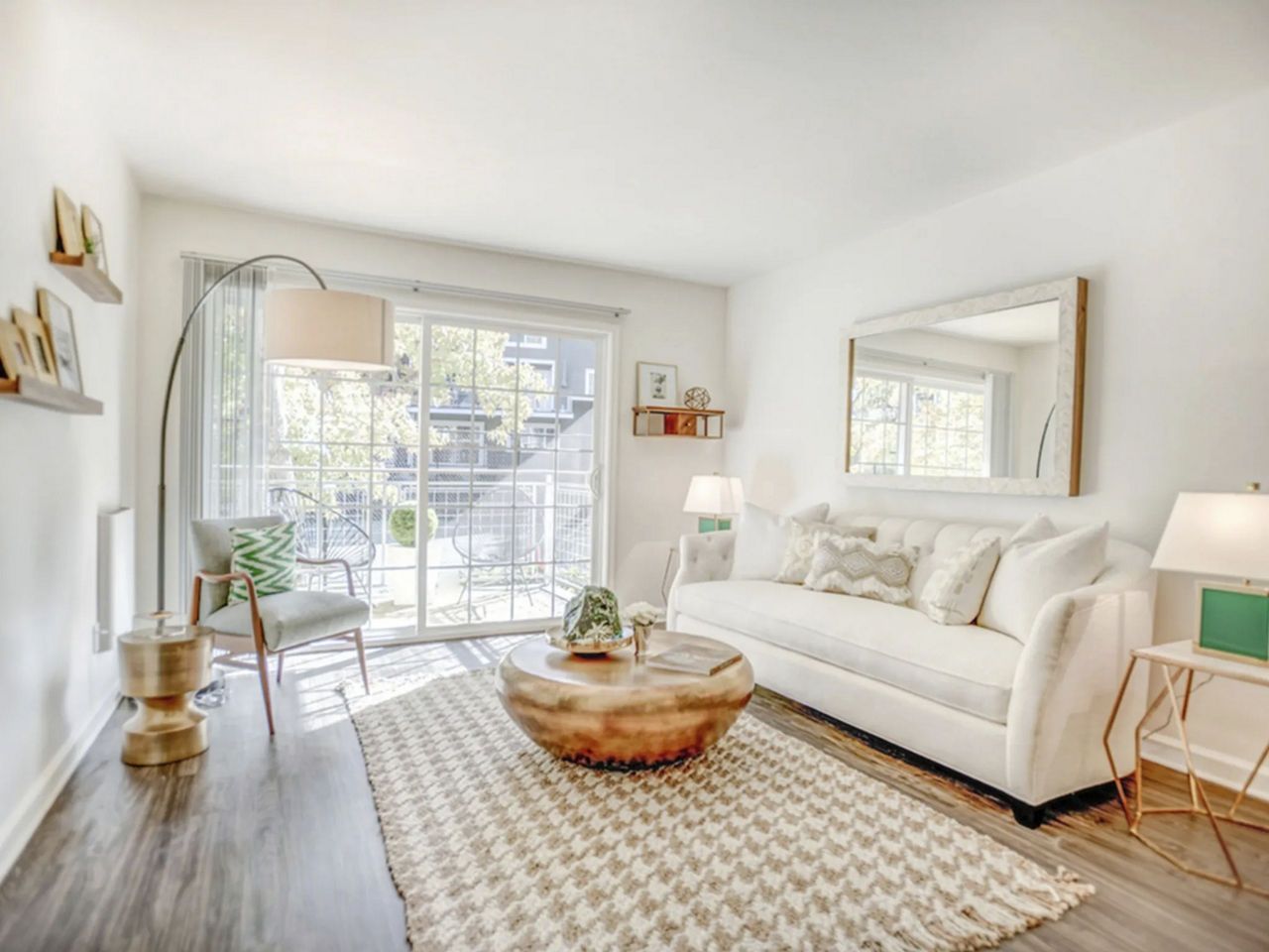 Bright living room with white couch, rug, and sliding glass door to a balcony.