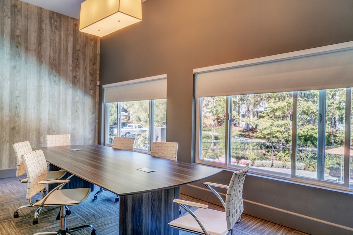 Conference room with a large wood table, white chairs, and big windows. Explore 1 and 2 bedroom apartments and townhomes in Larkspur, CA with modern floor plans and a convenient location just a 30-minute drive from San Francisco.