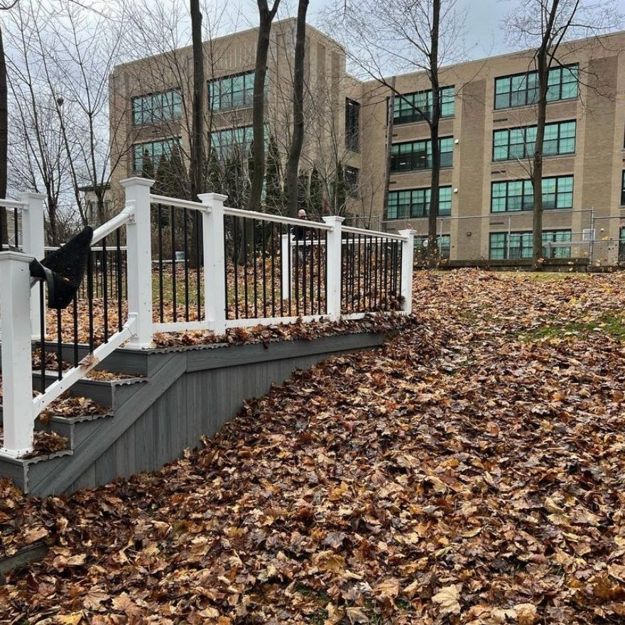 A staircase with a white railing and a large building in the background