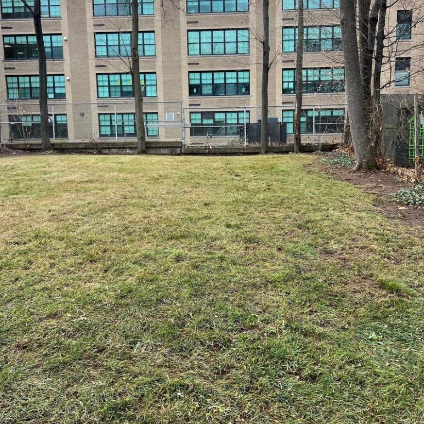 A large building with lots of windows is behind a grassy field