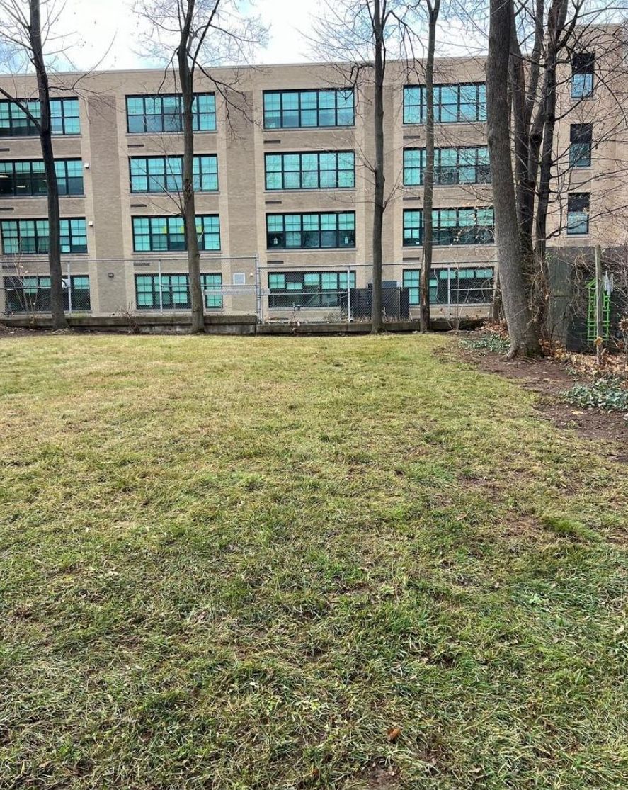 A large building with a lot of windows is behind a grassy field.