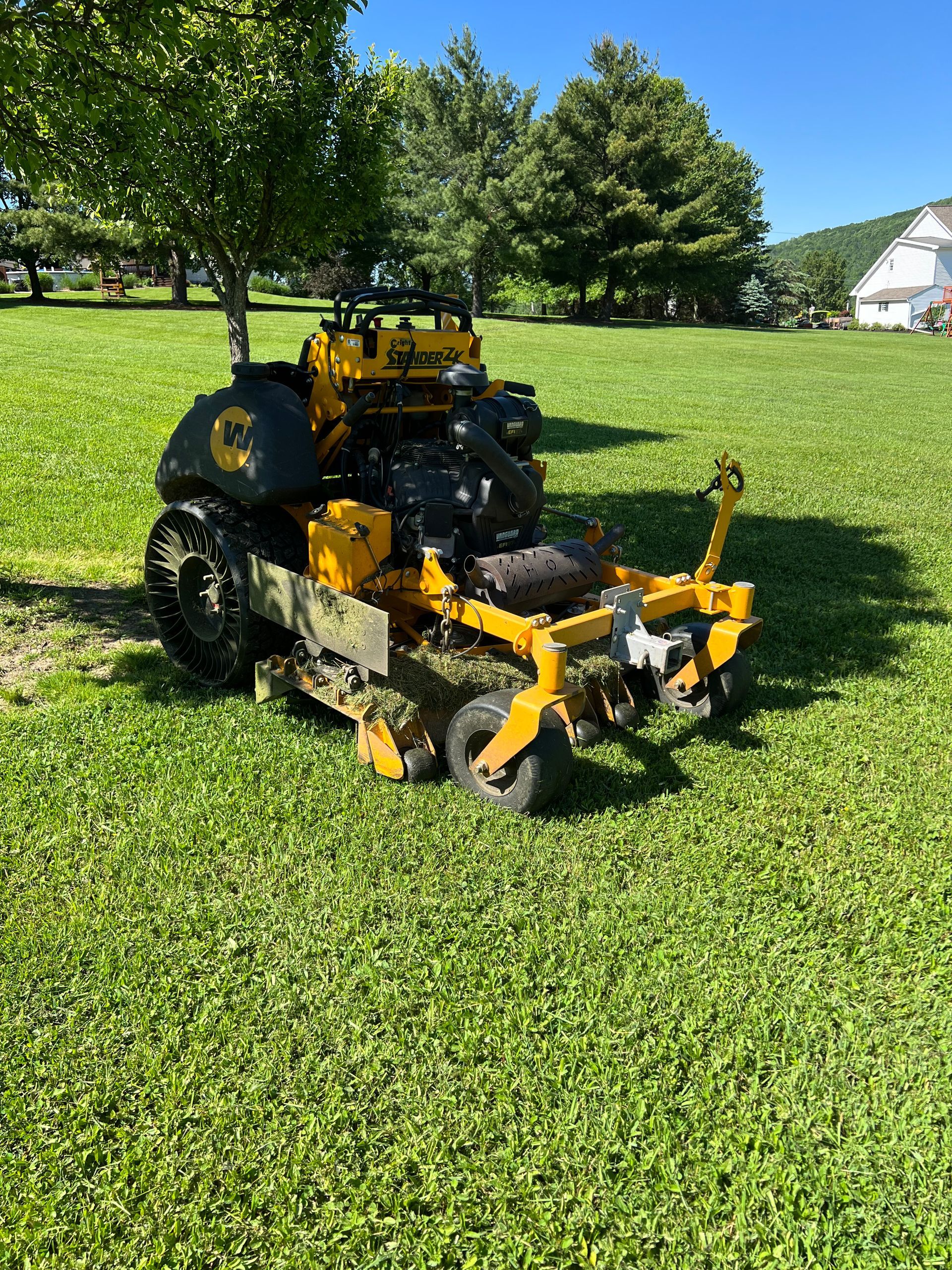 A yellow lawn mower is sitting in the middle of a lush green field.