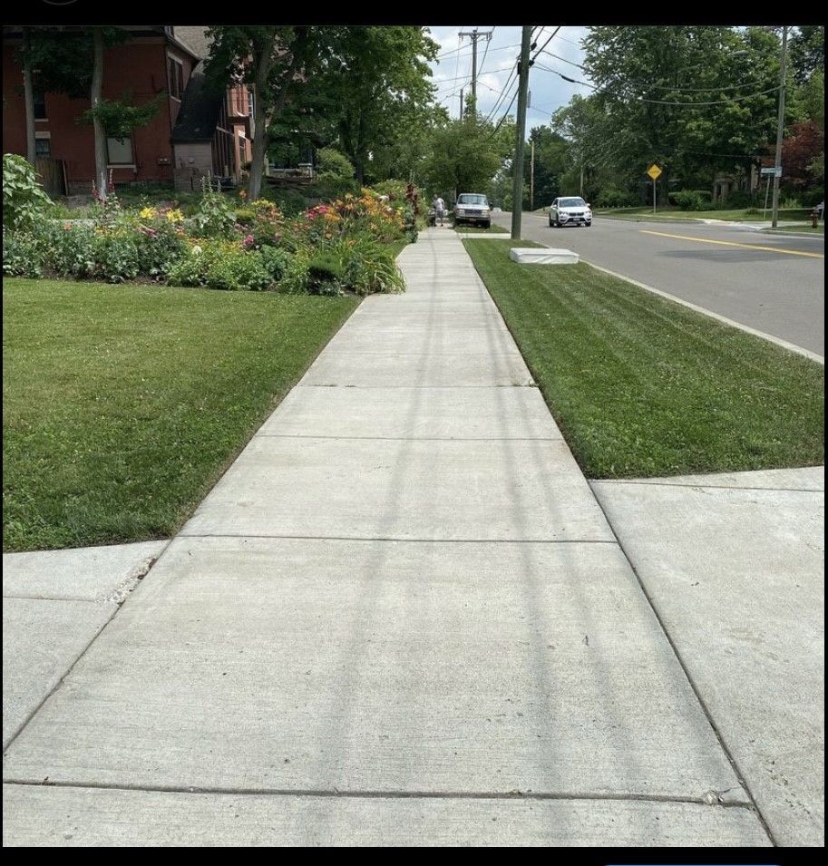 A sidewalk with grass on the side of it