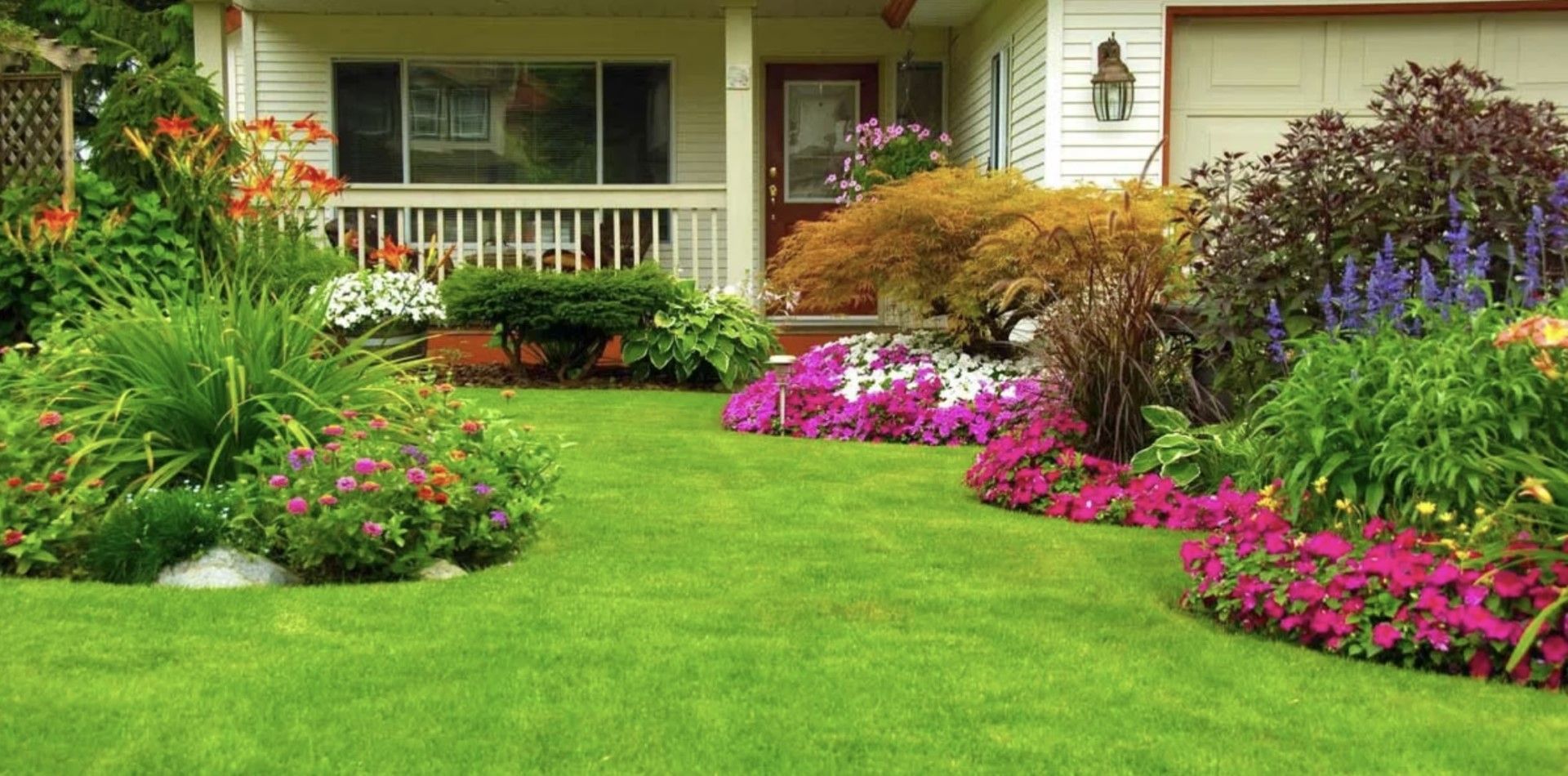 A house with a lush green lawn and flowers in front of it.
