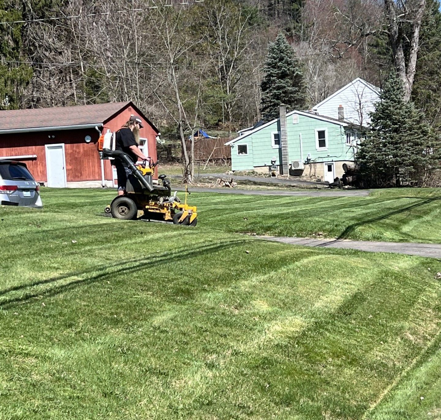 A man is riding a lawn mower on a lush green lawn.