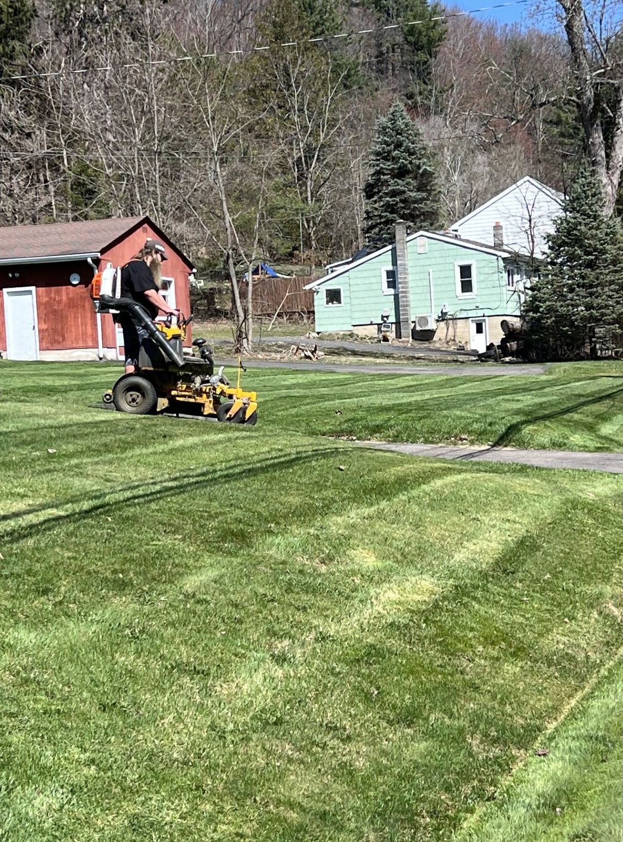 A man is riding a lawn mower on a lush green lawn.