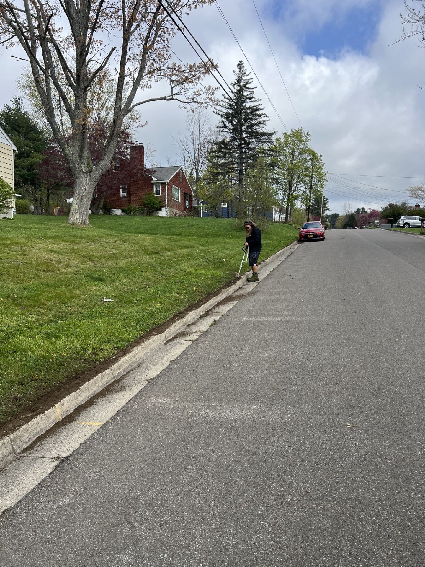 A person is mowing the grass on the side of the road.