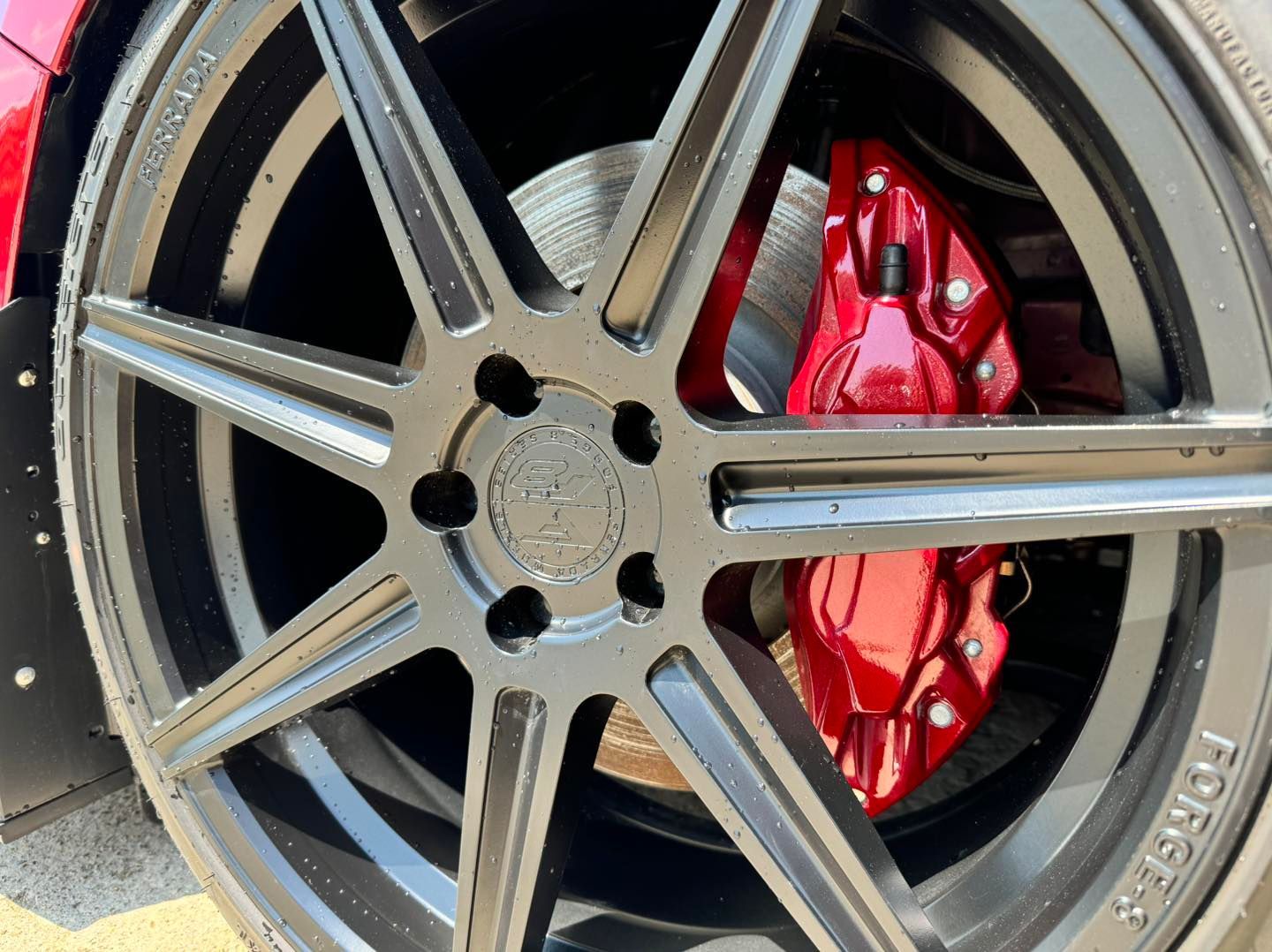 Close-up of a black car wheel with red brake calipers.