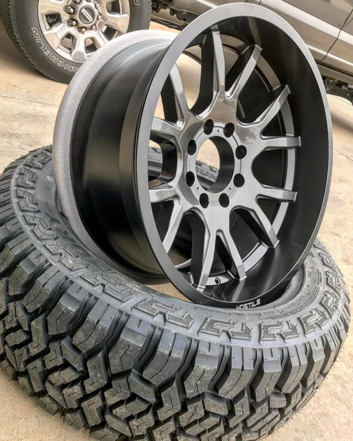 Black and silver car rim on a black off-road tire.