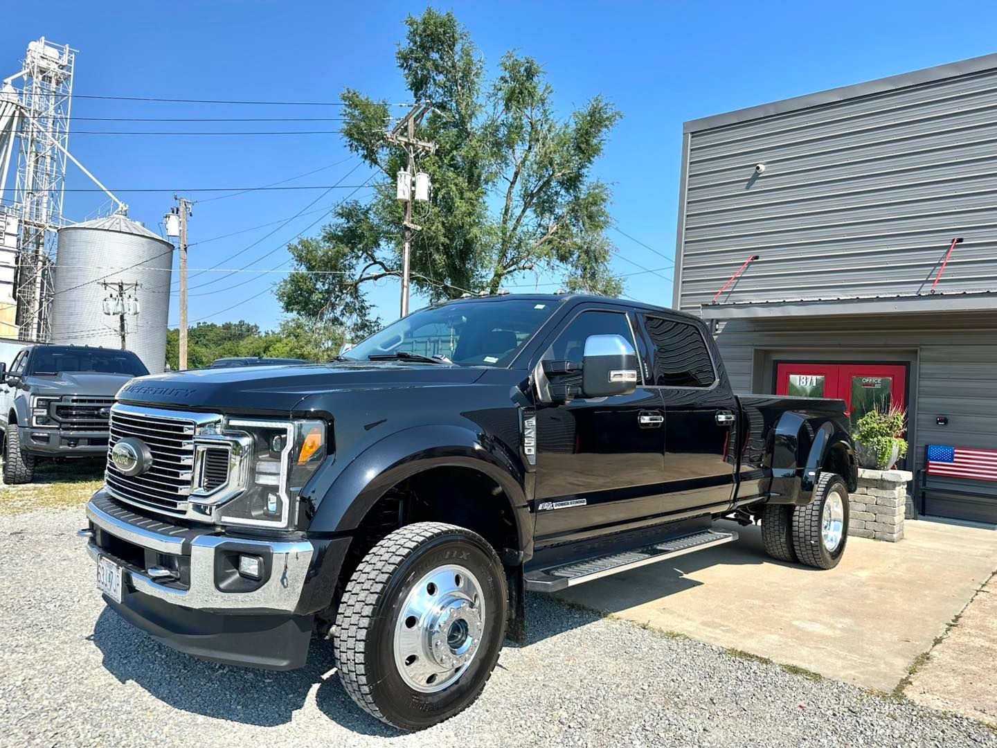 Black Ford F-350 dually pickup truck parked in front of a building on a sunny day.