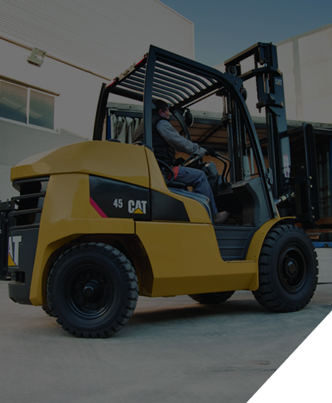 Carretilla elevadora CAT amarilla con operador, afuera de un edificio.