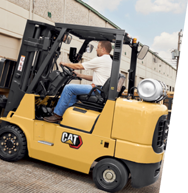 Hombre conduciendo una carretilla elevadora CAT amarilla. Almacén.