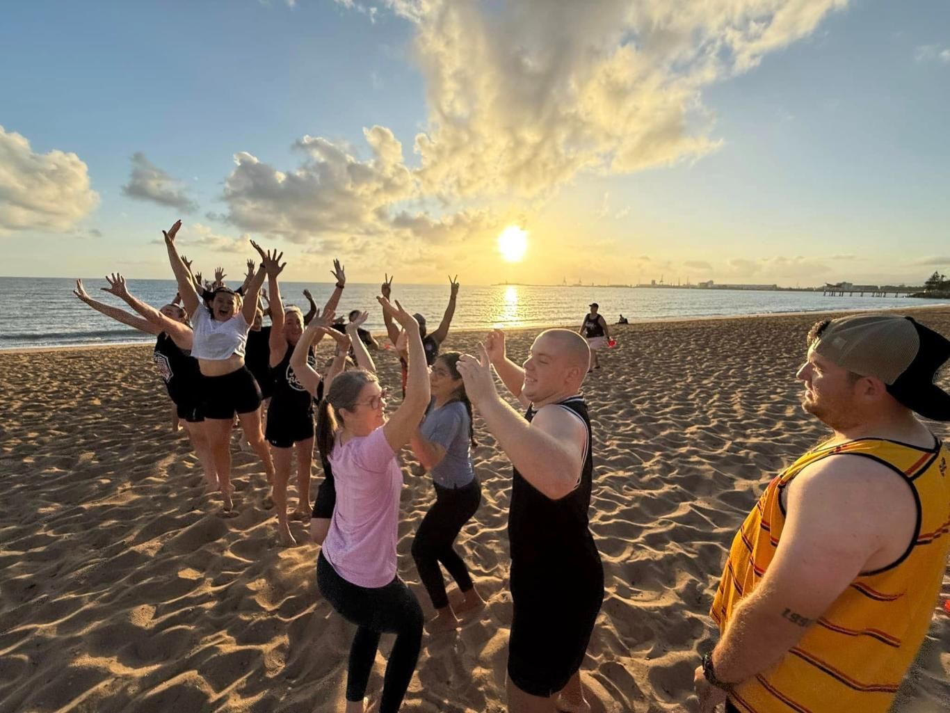 A Group Of People Are Dancing On The Beach At Sunset — Elev8ed Fitness In Currajong, QLD
