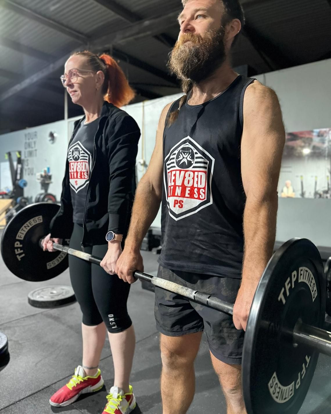 A Man And A Woman Are Holding Barbells In A Gym — Elev8ed Fitness In Currajong, QLD