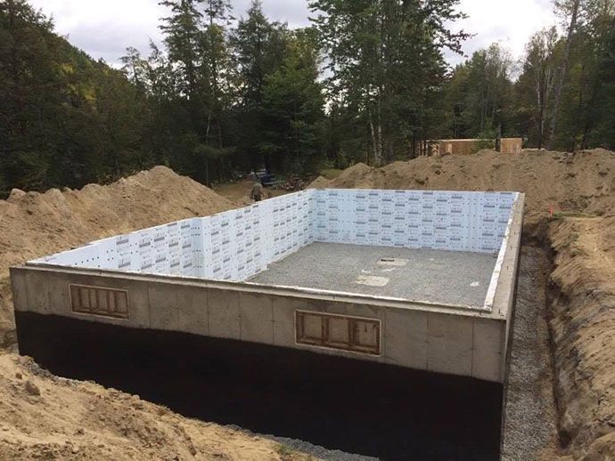Fondations pour un bâtiment, avec murs isolés. Socle en gravier et terre environnante.