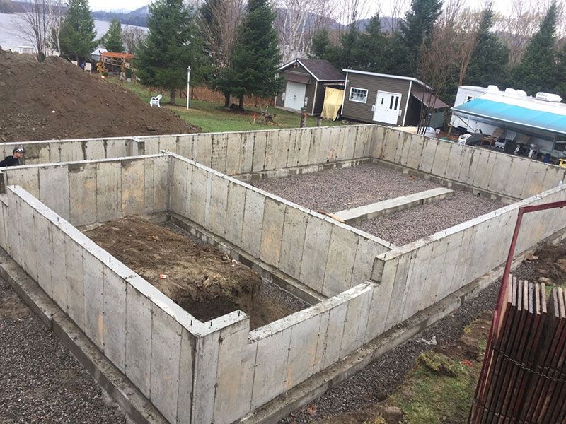 Murs de fondation en béton recouverts de gravier, prêts pour la construction dans une cour.