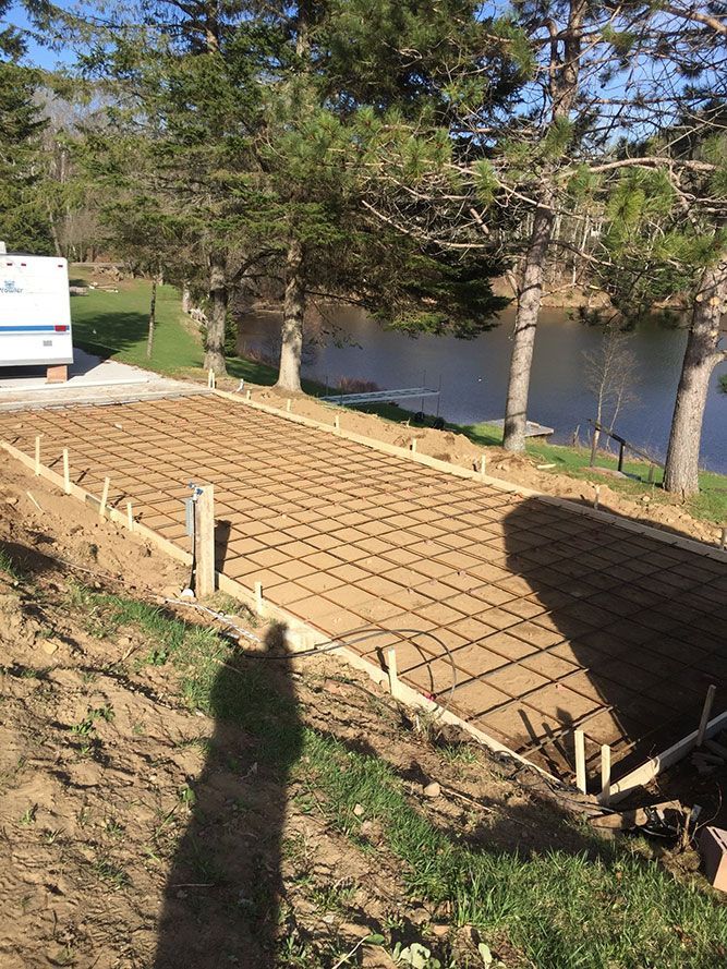 Fondation sur dalle de béton armé, à proximité d'un point d'eau et d'arbres.