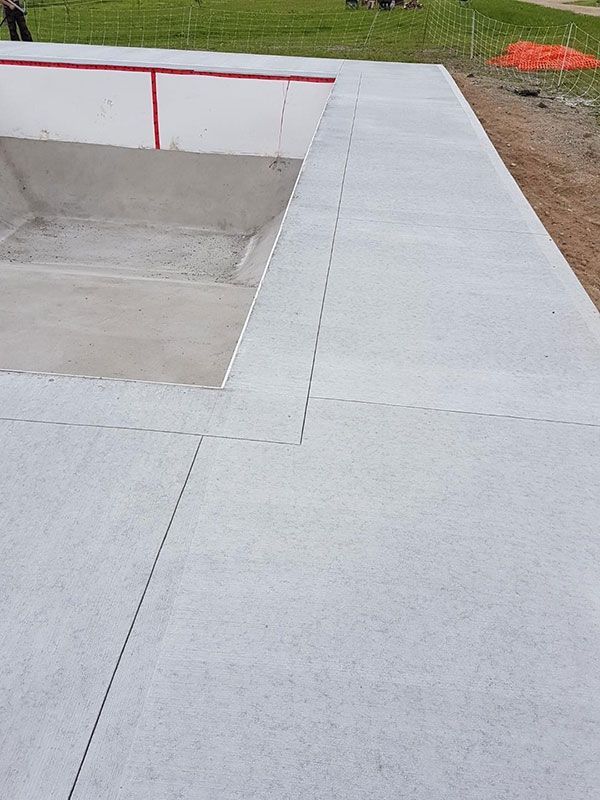 Travaux de bétonnage autour d'une piscine en construction.