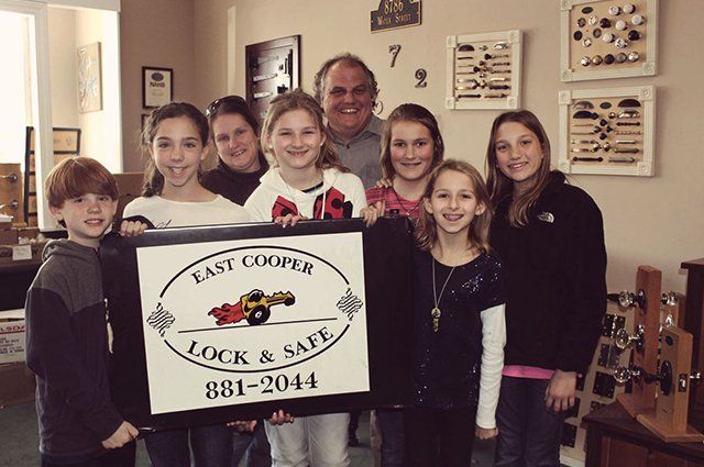 A group of people holding a sign that says east cooper lock & safe