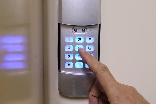 A person is pressing a keypad on a wall.