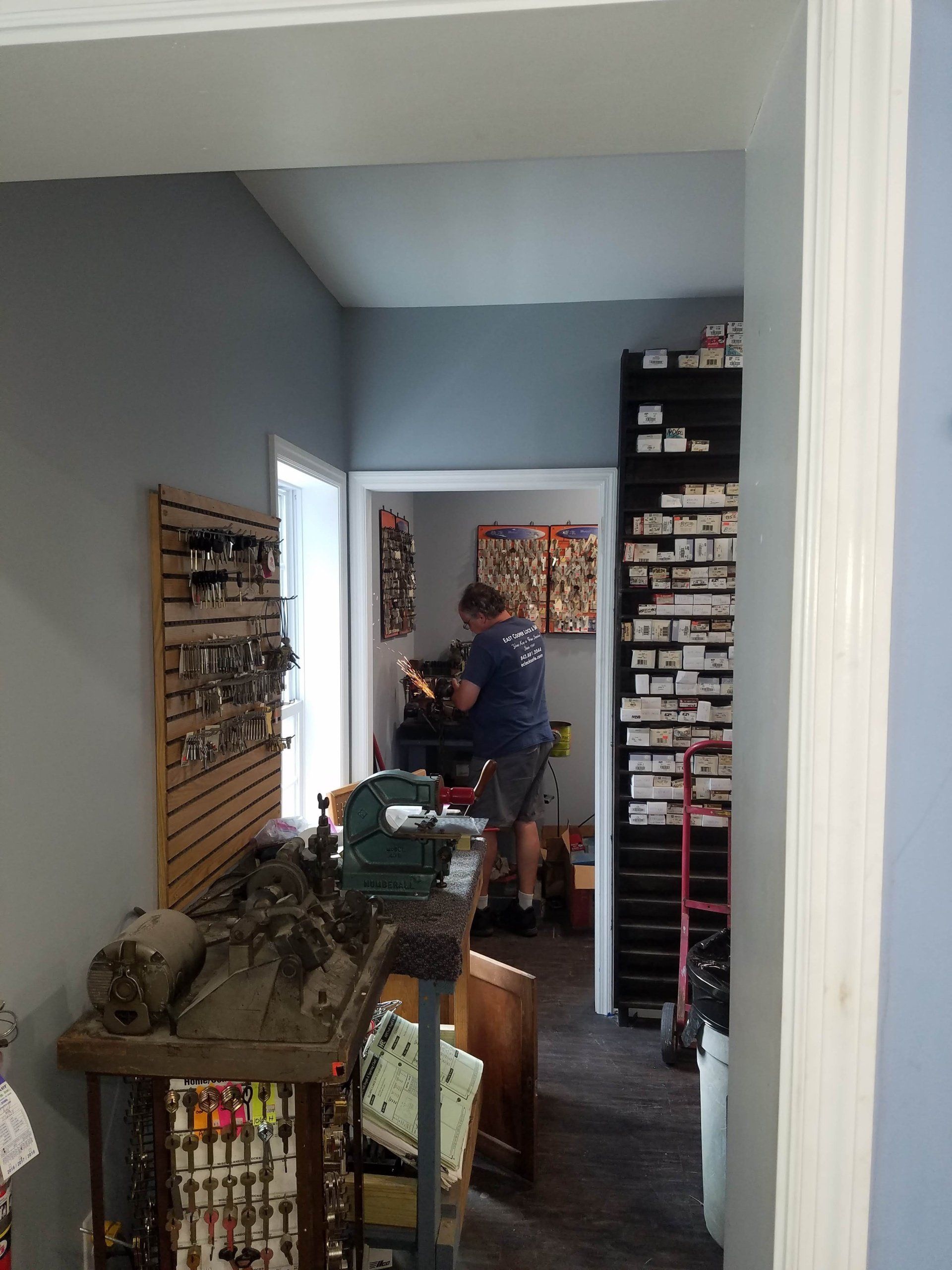 A man is working on a machine in a room with a lot of keys on the wall