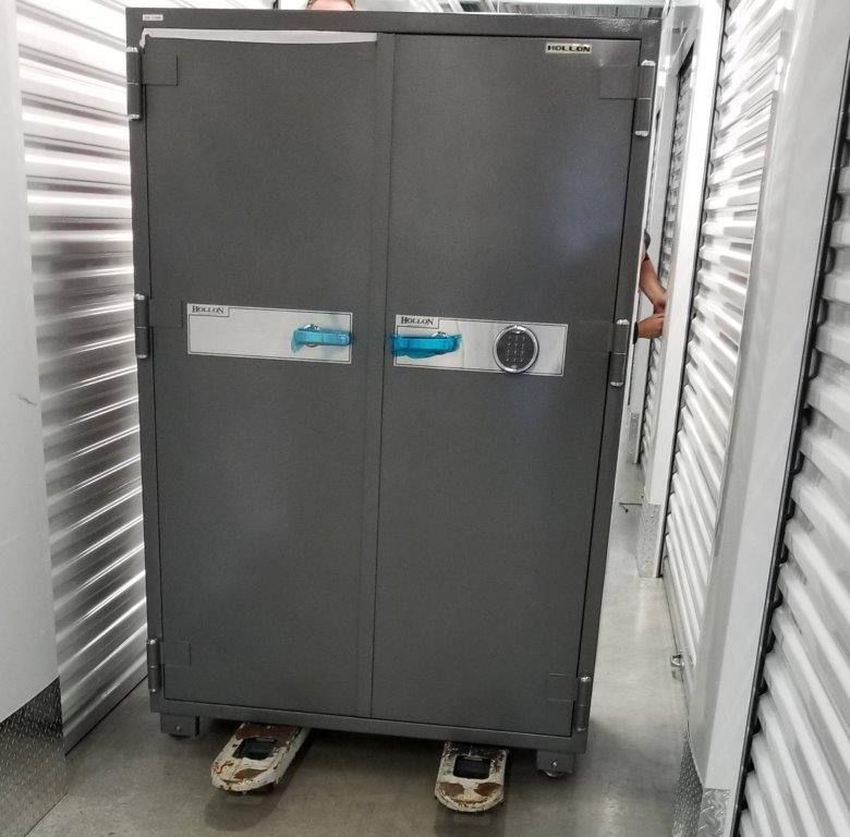 A man is standing next to a large safe