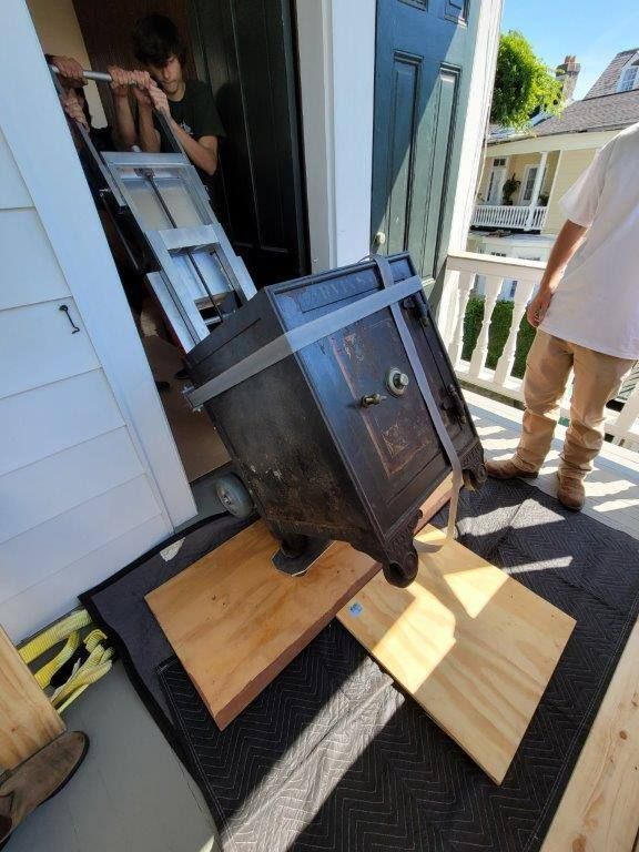 A man is standing next to a safe on wheels