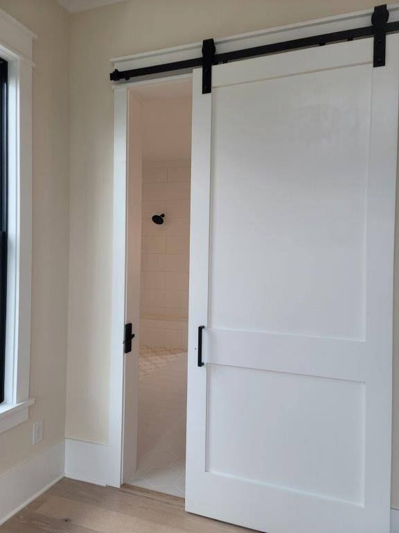 A bedroom with a sliding barn door leading to a bathroom.