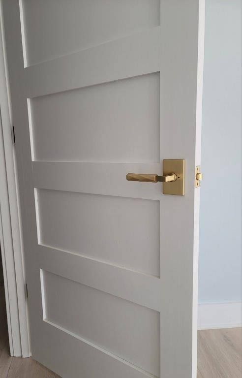 A white door with a gold handle is open in a room.