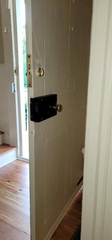 A door with a lock on it is open in a hallway.