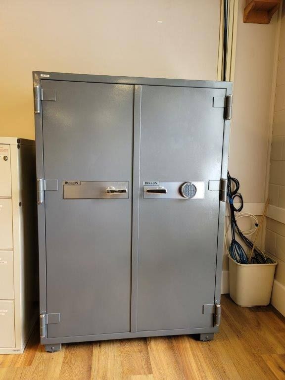 A large metal safe is sitting on a wooden floor in a room.