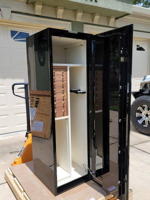 A black safe is sitting on top of a wooden table in front of a garage door.