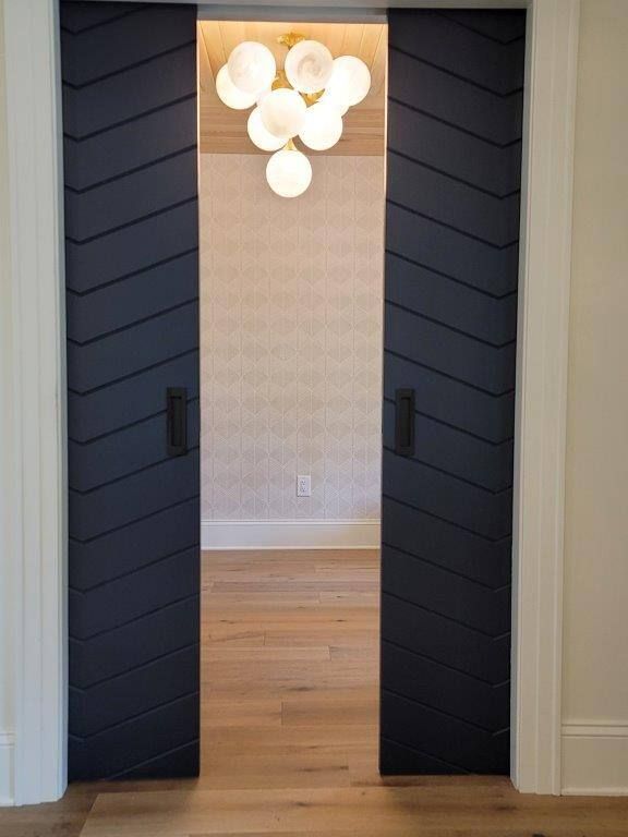 A pair of black sliding doors leading into a room with a chandelier hanging from the ceiling.