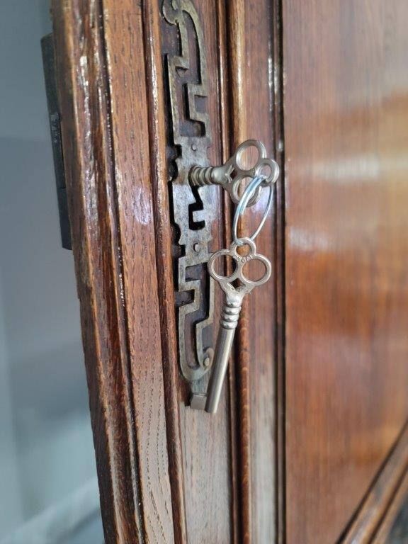 Two keys are hanging from a wooden door.