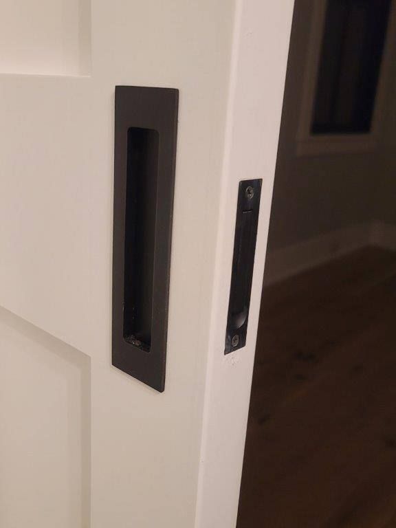 A close up of a black handle on a white door.