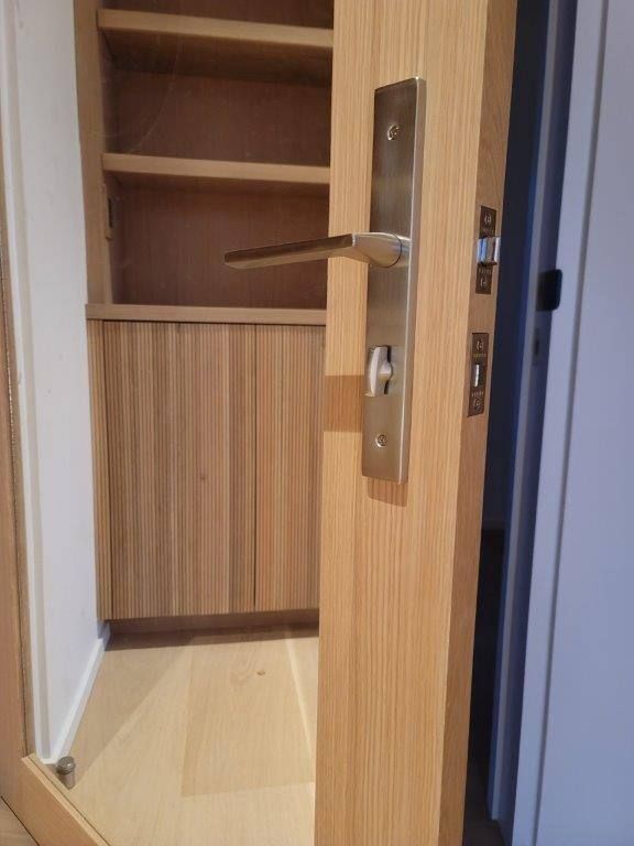 A wooden door with a stainless steel door handle