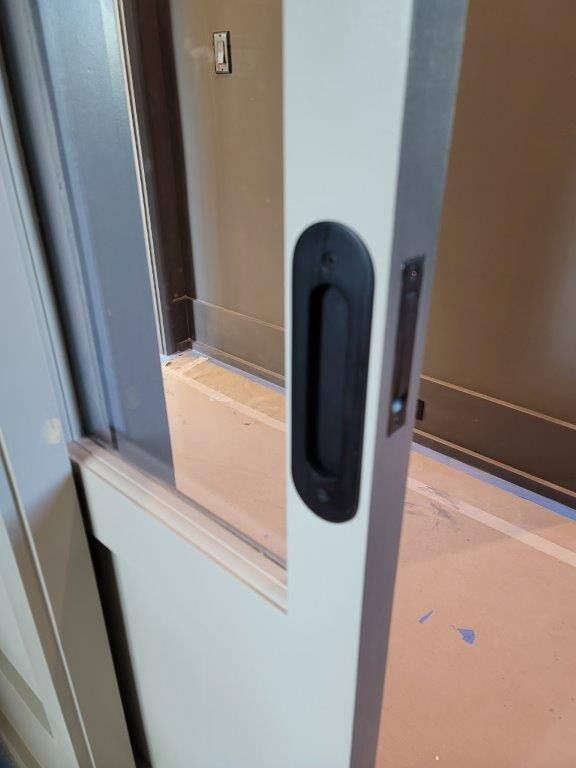 A close up of a sliding glass door with a black handle