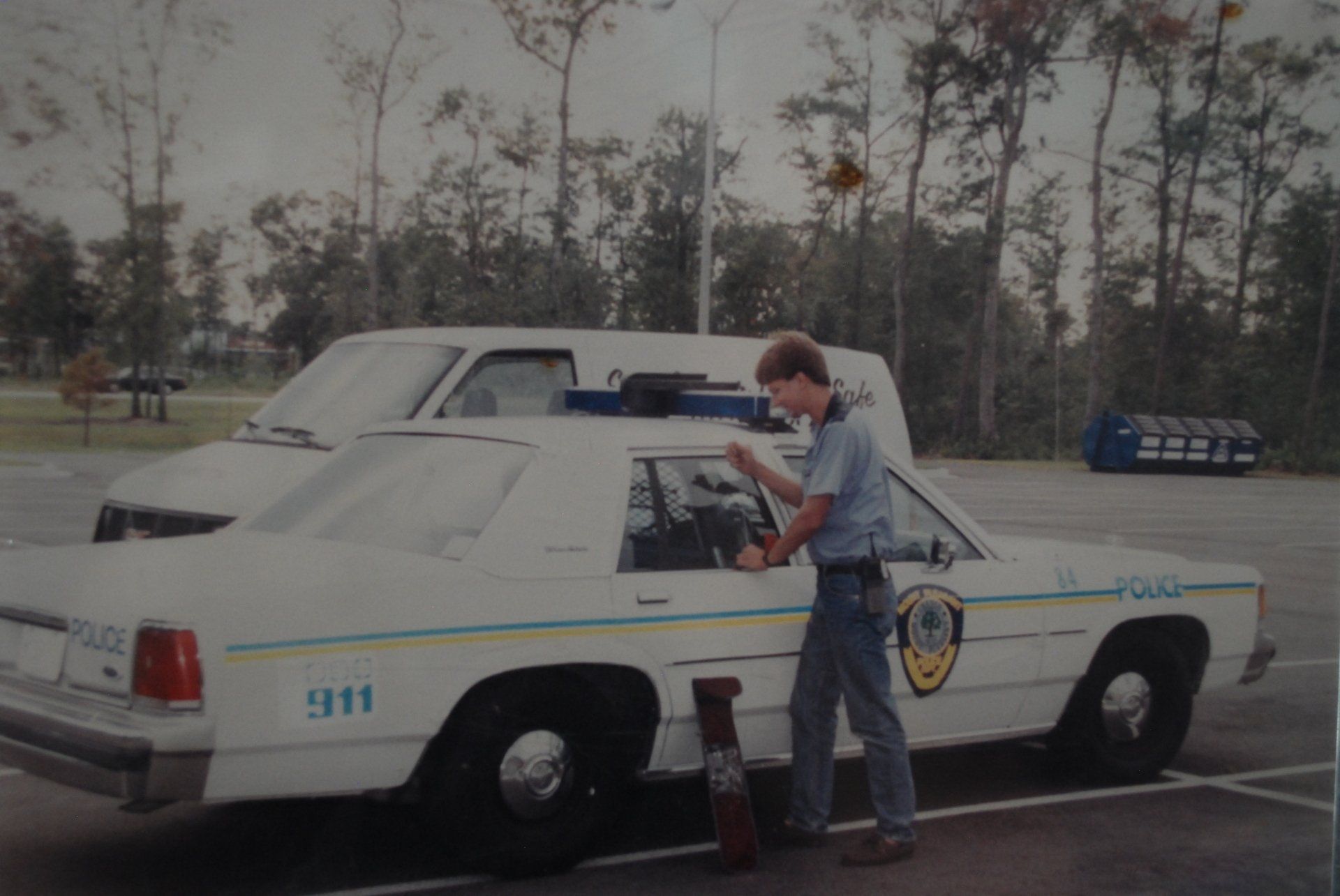 A man is standing next to a police car that says 911