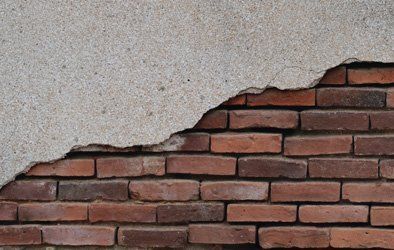 cracked plaster exposing brickwork  