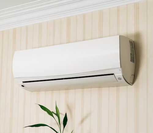 Wall-mounted white air conditioner on striped wallpaper, with a plant visible below.