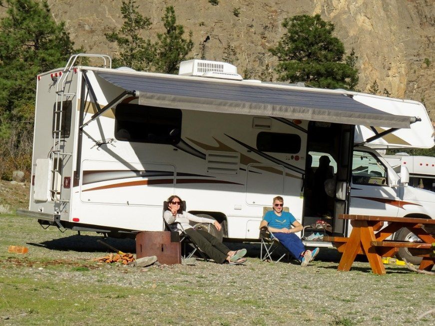Two People Relax Outside An Rv With Awning Extended, Mountain Backdrop — Canobolas Canvas In Orange, NSW