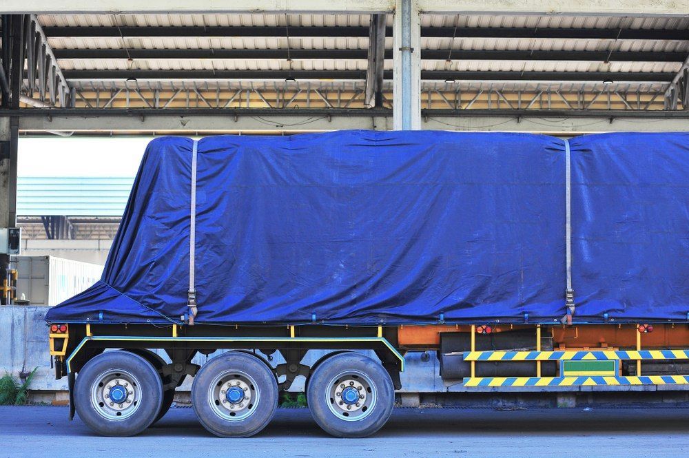 Blue-covered Semi-truck Parked Under A Loading Dock With Yellow And Black Hazard Stripes — Canobolas Canvas In Orange, NSW
