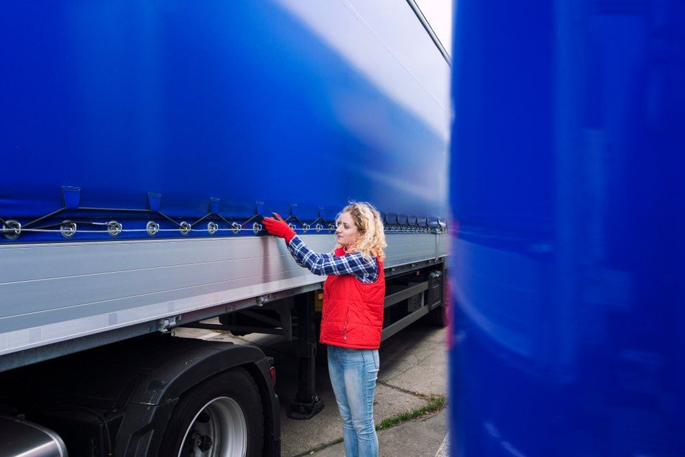 Woman In Red Vest Inspecting Blue Truck Tarp Outdoors — Canobolas Canvas In Orange, NSW