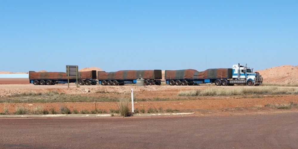 A Large Truck Pulling Several Trailers Driving On A Road Under A Clear Blue Sky — Canobolas Canvas In Orange, NSW