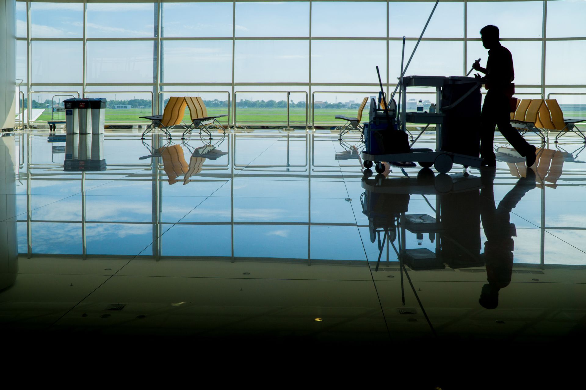 A man is mopping the floor in an airport waiting area