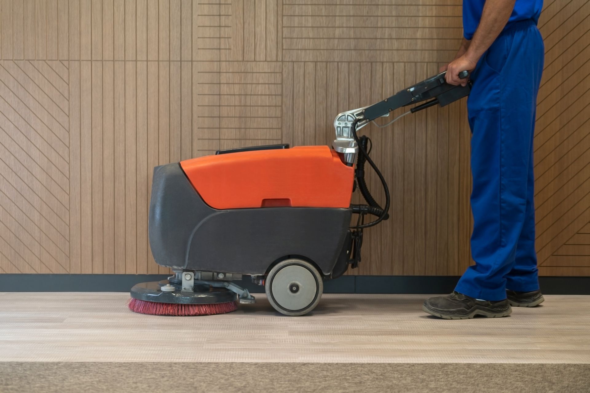 A man is cleaning a wooden floor with a machine.