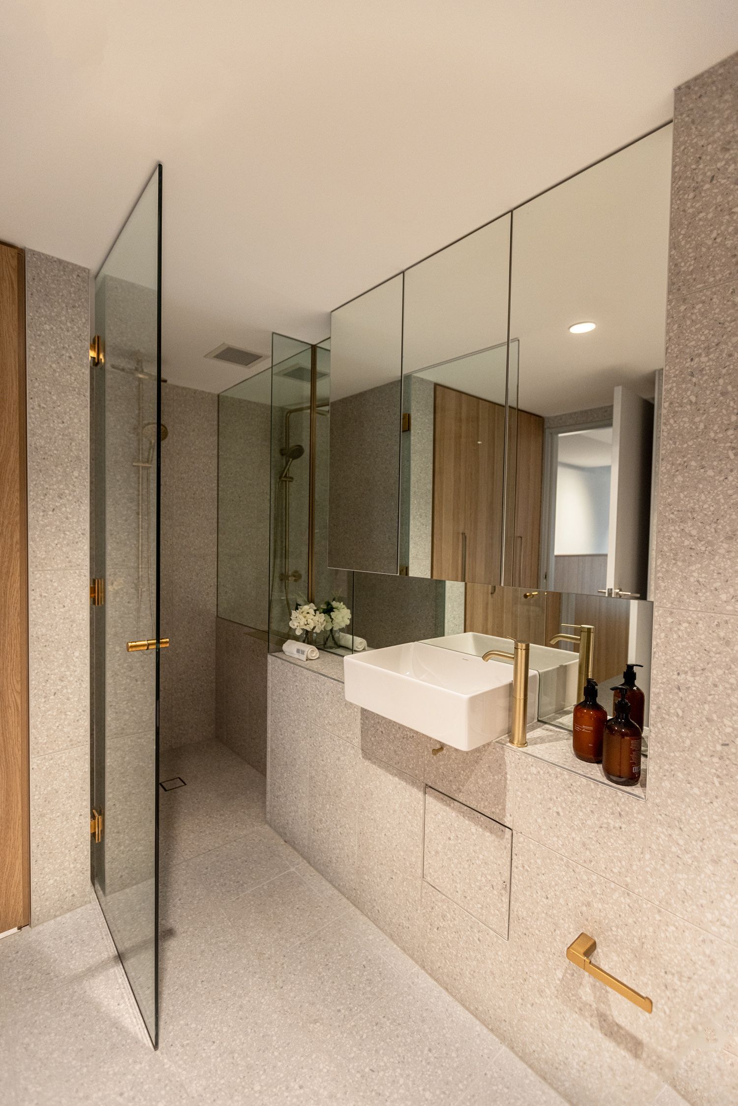 A bathroom with a sink, mirror and walk in shower.